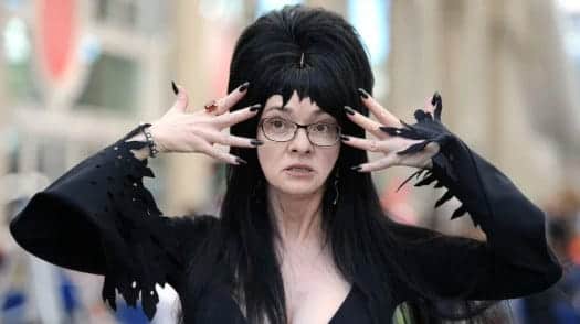 A person with long black hair and black nails

Description automatically generated