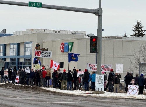 A group of people protesting outside a building

Description automatically generated